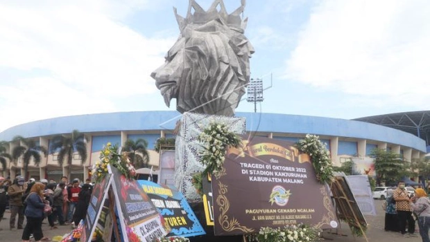 Warga berdoa di patung Singa Tegar kawasan Stadion Kanjuruhan yang dipenuhi karangan bunga di Malang, Jawa Timur, Senin, 3 Oktober 2022.