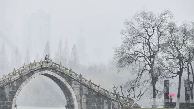 Sejumlah pengunjung berjalan-jalan di sebuah taman saat hujan salju di Kota Hefei, Provinsi Anhui, Tiongkok timur.