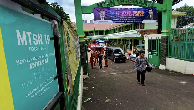 Warga melintas di depan gerbang di MTsN 19 Cilandak, di Jakarta, Jumat, 7 Oktober 2022.