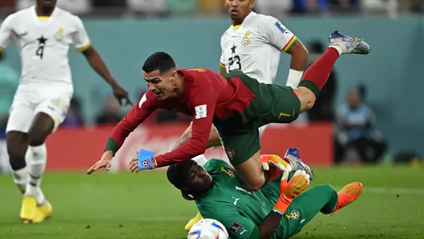 Penyerang Portugal, Cristiano Ronaldo, terjatuh saat berusaha mencetak gol dan bertabrakan dengan kiper Ghana, Ati Zigi dalam laga Piala Dunia, di Stadion 974, Kamis, 24 November 2022.