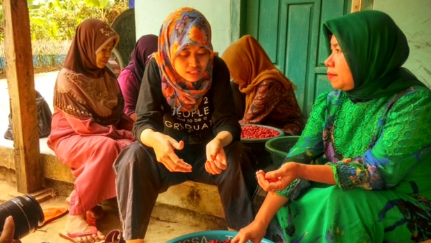 Salah satu relawan Menyapa Indonesia sedang berbincang dengan pelatih pengolahan kulit melinjo