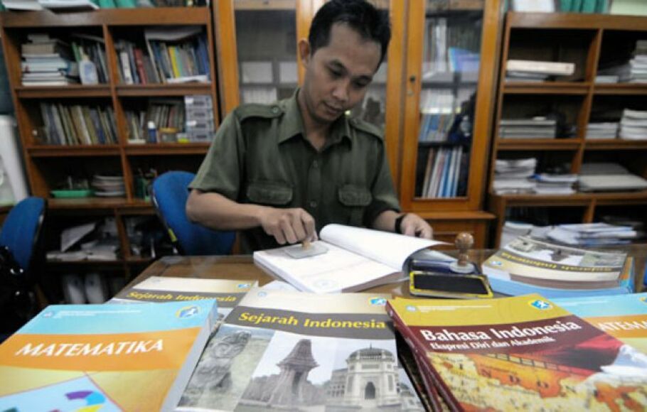 Seorang pegawai menyetempel buku pelajaran kurikulum 2013 di perpustakaan SMAN 68 Jakarta, Senin (15/7). 