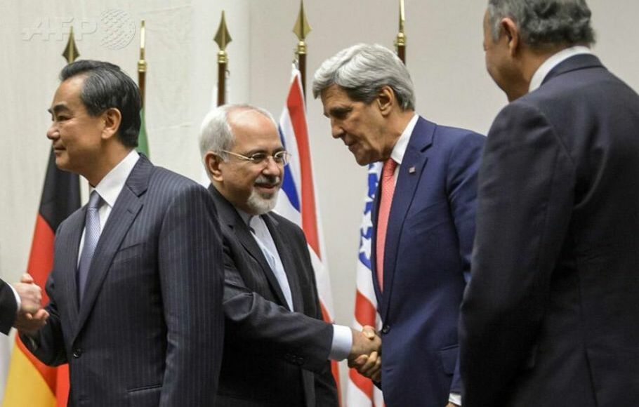 Menlu Iran Mohammad Javad Zarif berjabat tangan dengan Menlu AS John Kerry setelah meraih kesepakatan soal program nuklir di Jenewa, 24 November 2013.