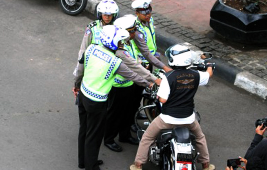 Petugas kepolisian memberhentikan pengendara motor ketika melintas di jalan MH Thamrin, Jakarta.