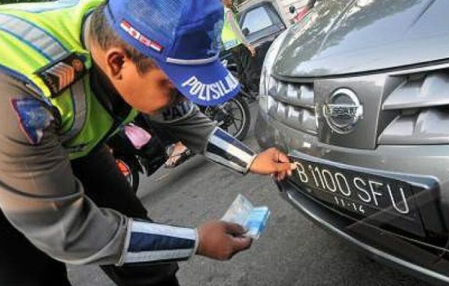 Polisi lalu lintas saat mengecek pelat nomor kendaraan.