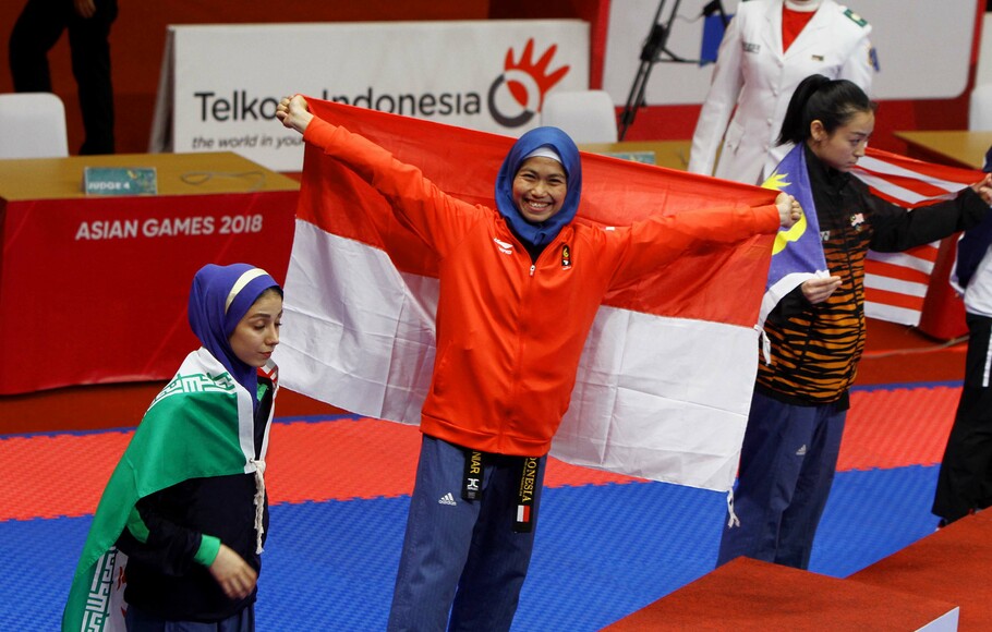 Atlet taekwondo putri Indonesia, Defia Rosmaniar (tengah) sesaat sebelum pengalungan medali, usai memenang nomor poomsae tunggal putri taekwondo di Asian Games 2018 di Jakarta Convention Center (JCC), Minggu 19 Agustus 2018. SP/Joanito De Saojoao.