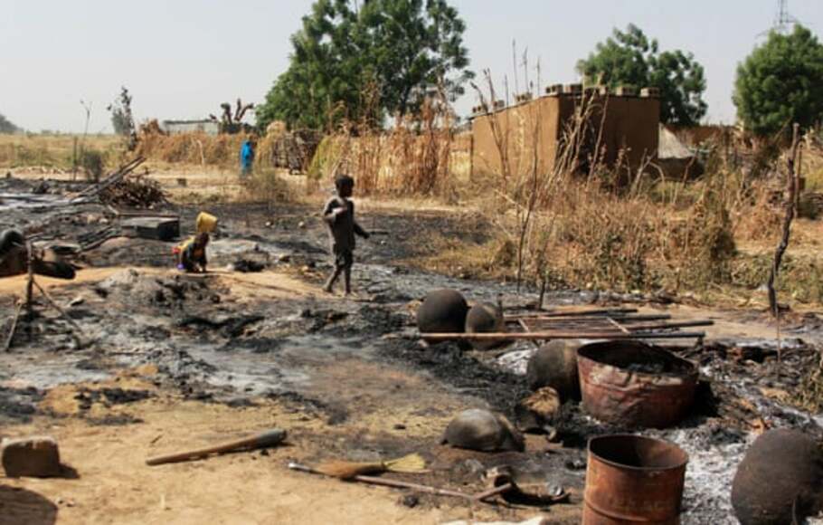 Seorang anak laki-laki berjalan melewati sisa-sisa puing rumah di desa yang dibakar oleh Boko Haram di pinggiran Maiduguri.