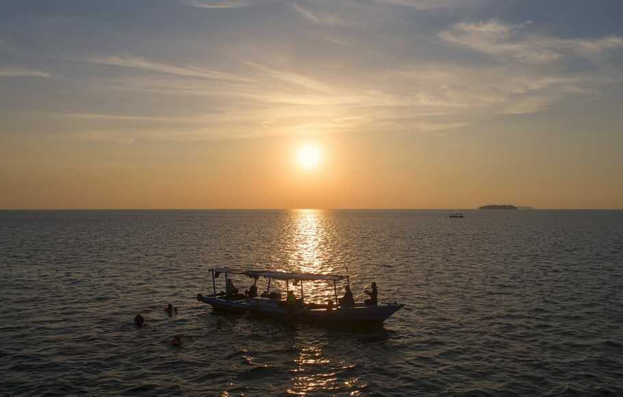Wisatawan naik perahu menuju ke tengah laut di sore hari di dekat Pulau Panggang, Kepulauan Seribu.