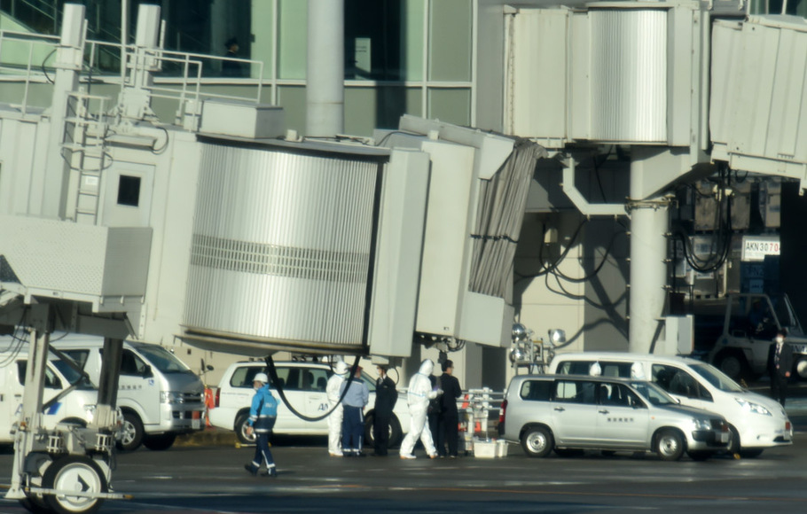 Pekerja Bandara Haneda Jepang dengan alat pelindung di dekat pesawat yang mmengevakuasi warga Jepang dari Wusan, Tiongkok, Rabu (29/1)