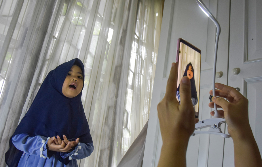 Seorang ibu merekam video anaknya ujian hafalan sekolah untuk dikirim ke guru dengan gawai dari rumah, karena sekolah terhenti selama pembatasan sosial berskala besar (PSBB) di Kota Pekanbaru, Riau, Selasa 28 April 2020.
