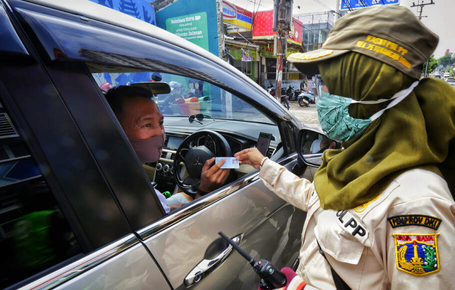Petugas memeriksa surat kelengkapan kendaraan dan juga Surat Izin Keluar Masuk (SIKM) Jakarta saat razia plat nomor kendaraan luar Jakarta di Jalan Ciledug Raya, Petukangan Utara, Jakarta, Jumat, 29 Mei 2020. 