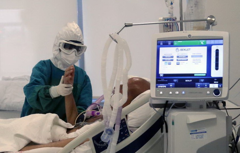 Ilustrasi seorang pekerja medis merawat pasien Covid-19 di ICU rumah sakit.