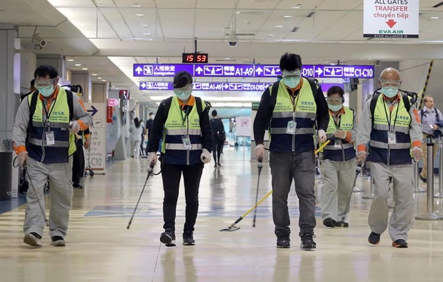 Para pekerja yang masker melakukan disinfeksi di area Bandara Internasional Taoyuan, Taiwan, Rabu (22/1/2020), di tengah pandemi Covid-19. 
