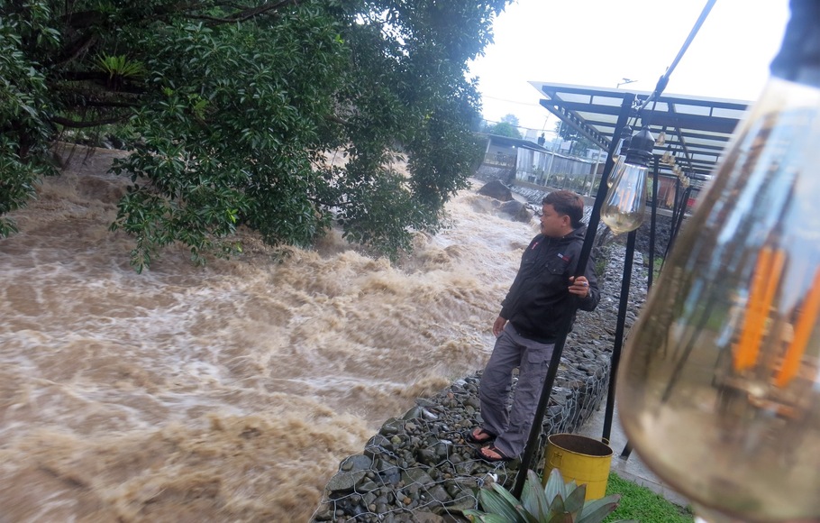 Warga melihat luapan Sungai Ciliwung di Cisarua, Kabupaten Bogor, Jawa Barat, Minggu 7 Februari 2021. Tingginya intensitas curah hujan di wilayah Puncak, Kabupaten Bogor menyebabkan naiknya ketinggian muka air di sepanjang aliran Sungai Ciliwung. 