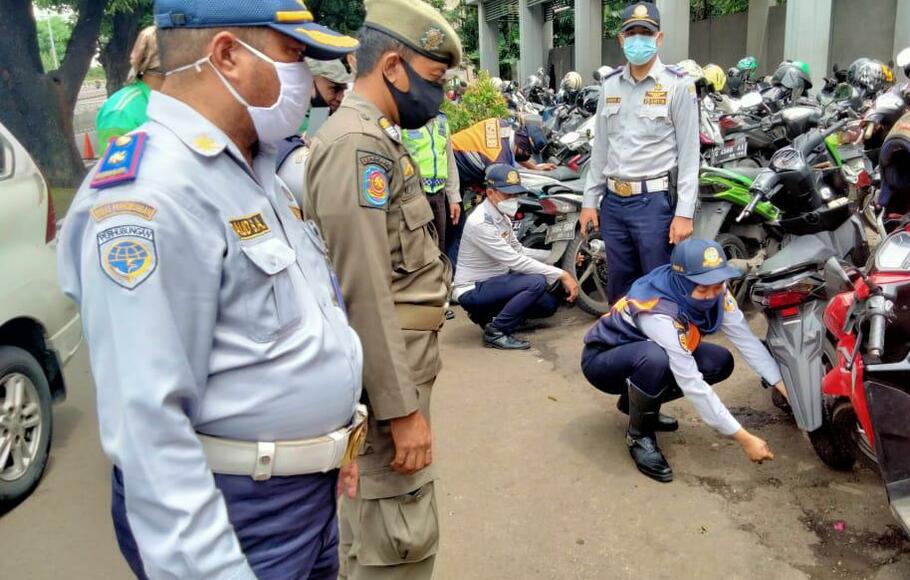 Petugas mencabut pentil ban sepeda motor yang parkir liar, di depan Kalibata City, Pancoran, Jakarta Selatan.