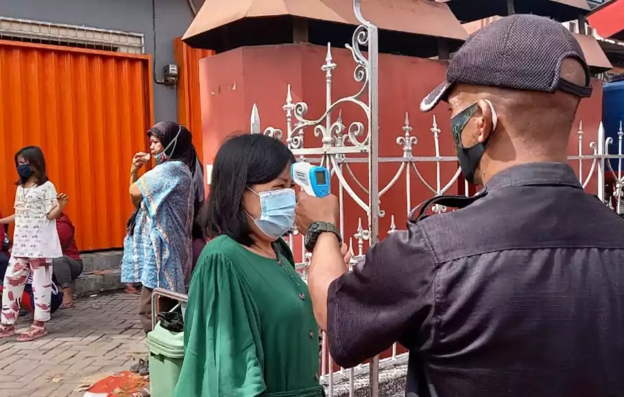 Pengunjung dicek suhu tubuhnya sebelum memasuki Kelenteng Boen Tek Bio, Kota Tangerang untuk melaksanakan ibadah dalam rangka Tahun Baru Imlek, Jumat, 12/2/2021.