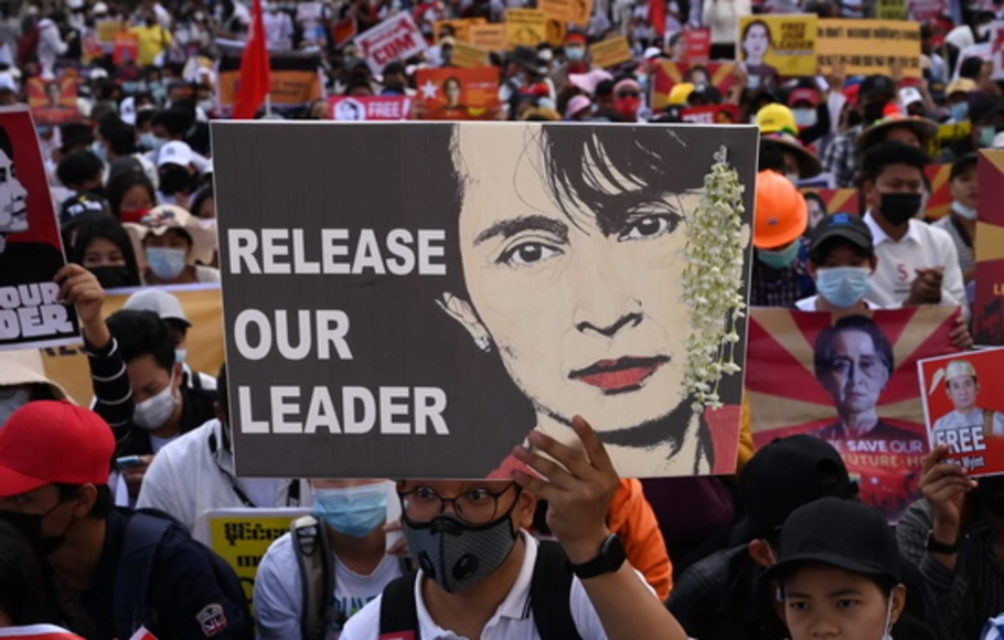 Seorang pengunjuk rasa memegang poster yang menyerukan pembebasan pemimpin sipil Myanmar yang ditahan Aung San Suu Kyi ketika demonstran memblokir jalan selama demonstrasi menentang kudeta militer di Yangon, Rabu (17/2/2021).