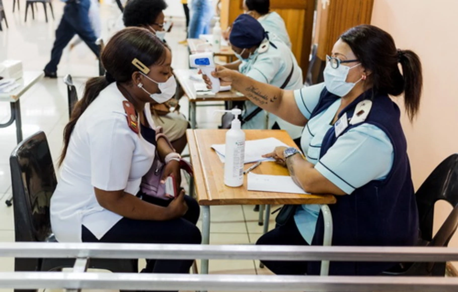 Seorang perawat mendapatkan pemeriksaan suhu sebelum menerima dosis vaksin Covid-19 buatan Johnson & Johnson untuk melawan virus corona  saat Afrika Selatan melanjutkan kampanye inokulasi di Rumah Sakit Prince Mshiyeni di Umlazi, selatan Durban, Kamis (18/2/2021).