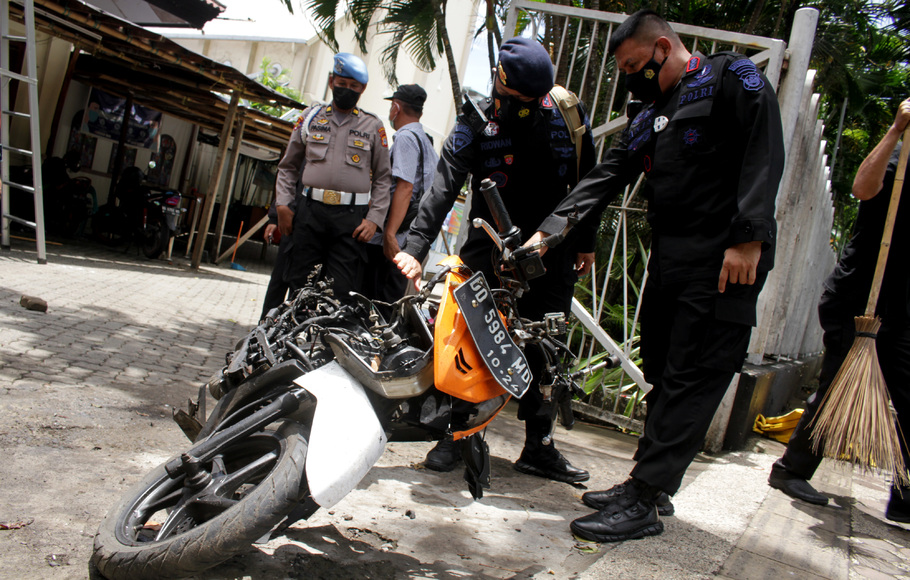 Anggota polisi mengamati motor yang digunakan terduga pelaku bom bunuh diri sebelum dievakuasi di depan Gereja Katedral Makassar, Sulawesi Selatan, Senin, 29 Maret 2021.