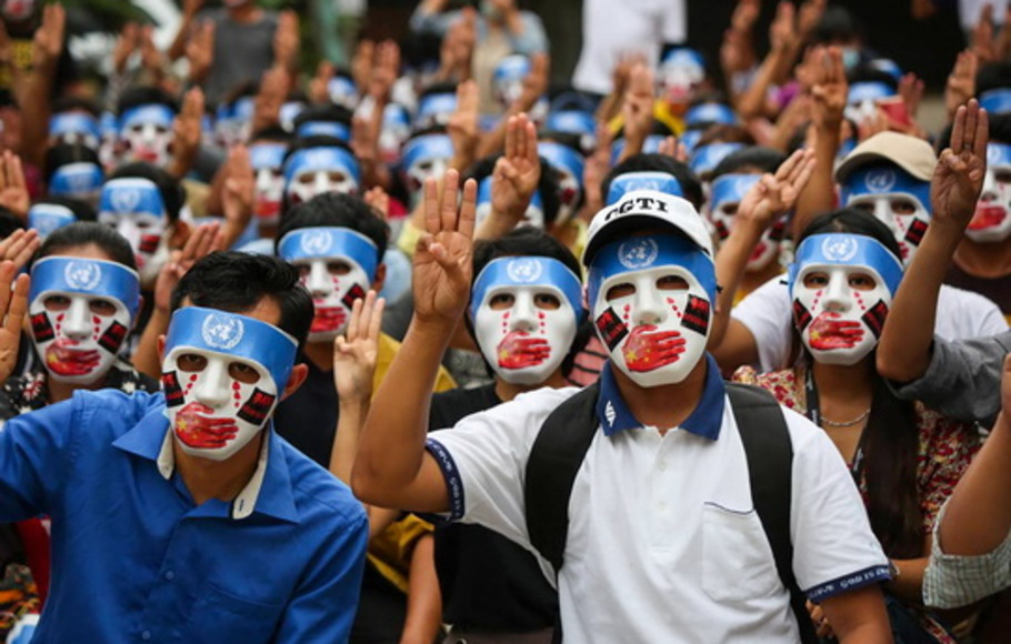 Para pengunjuk rasa memberi hormat tiga jari sambil mengenakan topeng yang mengungkapkan simbol campur tangan Tiongkok dalam penanganan PBB atas urusan Myanmar setelah kudeta militer di Yangon, Myanmar, Minggu 4 April 2021. 
