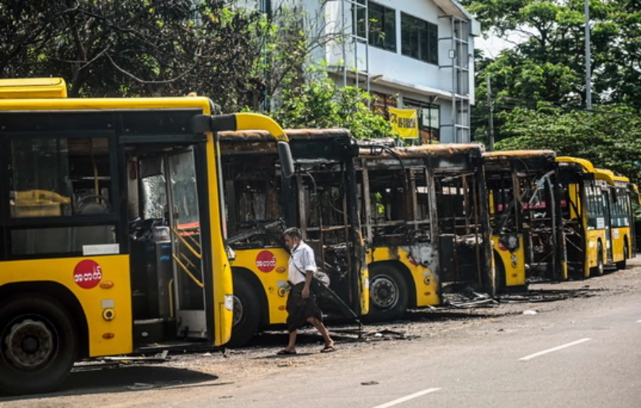 Seorang pria berjalan melewati deretan bus Yangon Bus Service (YBS), yang dibakar di Yangon, Myanmar pada Selasa 12 April 2021, karena negara itu masih dalam kekacauan setelah kudeta militer Februari