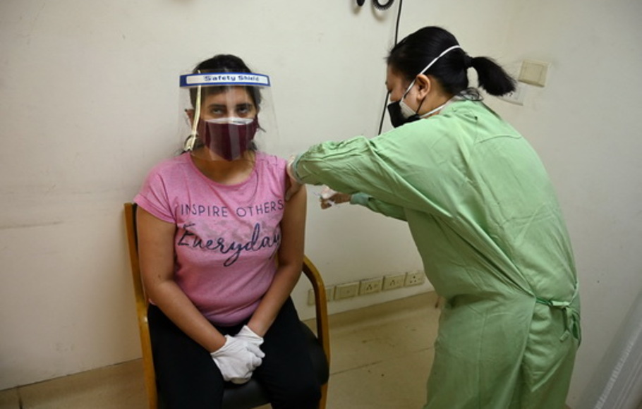 Seorang pekerja medis menyuntik seorang wanita dengan dosis Covishield, vaksin coronavirus Covid-19 Astrazeneca-Oxford, di rumah sakit Max, New Delhi, India pada Sabtu 1 Mei 2021 saat hari pertama kampanye vaksinasi India untuk semua orang dewasa. 