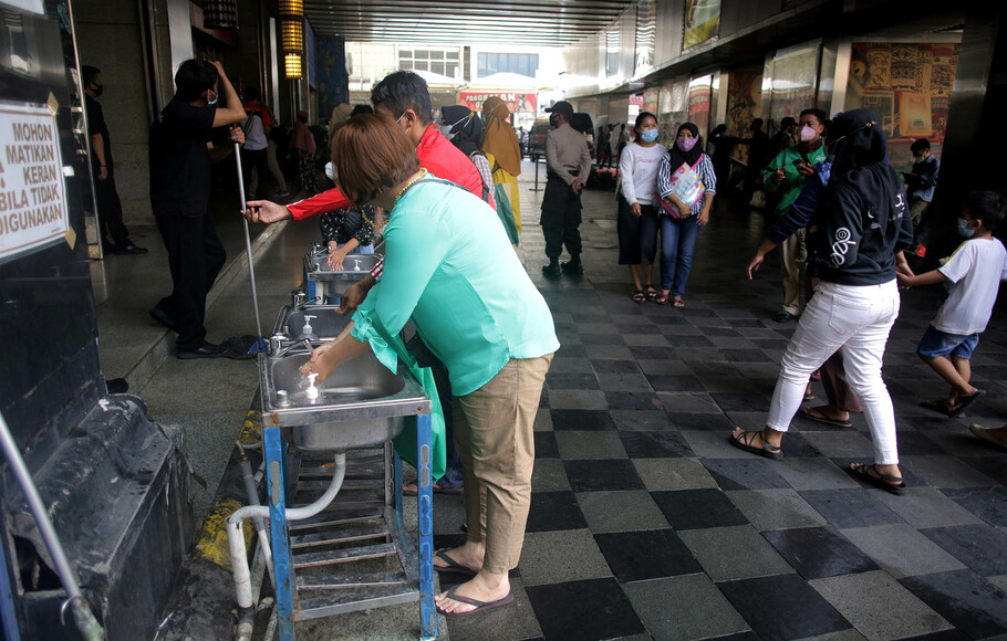 Pengunjung mencuci tangan sebelum masuk ke tempat berbelanja di Blok A Tanah Abang, Jakarta Pusat, Minggu 2 Mei 2021.