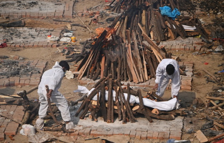 Kerabat menyiapkan tumpukan kayu bakar untuk orang yang mereka cintai, yang meninggal karena virus corona Covid-19, sebelum dikremasi di tempat kremasi di New Delhi, India pada Minggu 2 Mei 2021. 
