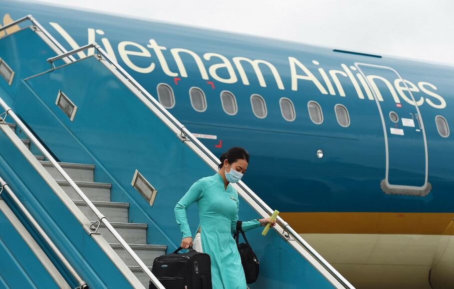 Seorang awak pesawat Vietnam Airlines yang mengenakan masker di tengah kekhawatiran penyebaran virus corona Covid-19 turun dari  penerbangan kembali dari Taiwan di Bandara Internasional Noi Bai, Hanoi pada 3 Maret 2020. 