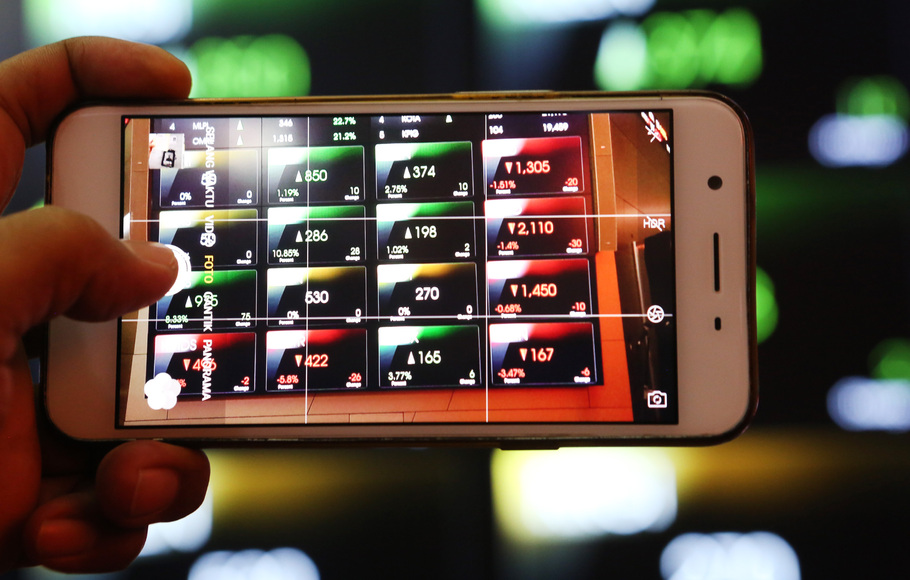 Pengunjung memotret monitor indeks saham mengunakan ponsel di Bursa Efek Indonesia (BEI), Jakarta.