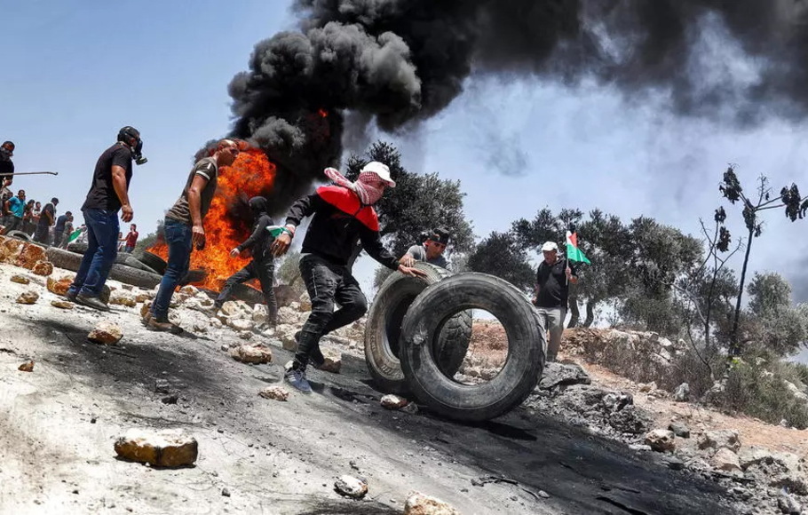 Pengunjuk rasa Palestina membakar ban saat bentrokan dengan pasukan keamanan Israel di desa Beita, selatan Nablus, di Tepi Barat yang diduduki.