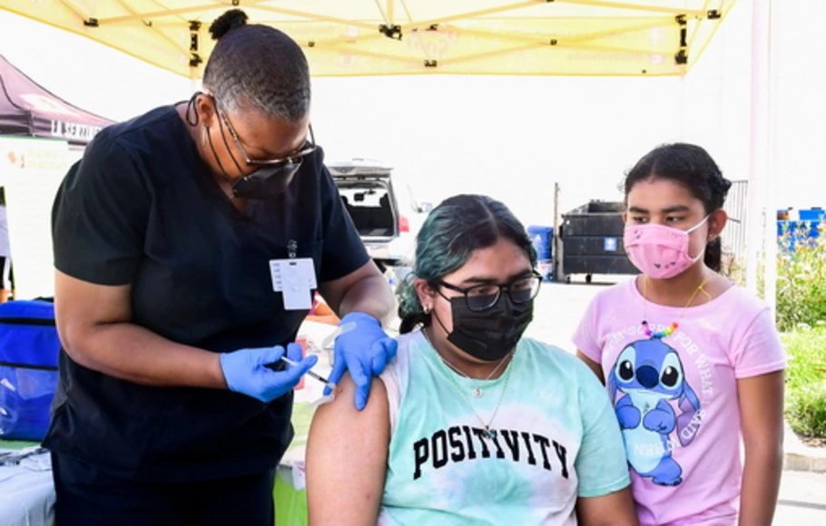 Brenda Vargas, remaja 14 tahun, menerima vaksin Pfizer Covid-19 dari perawat kejuruan Eon Walker di klinik vaksin keliling yang diselenggarakan oleh Mothers in Action dan dioperasikan oleh Los Angeles County of Public Health di Los Angeles, California, AS, Jumat 16 Juli 2021. 