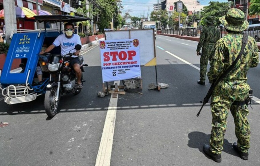 Polisi berjaga-jaga di pos pemeriksaan saat karantina wilayah diberlakukan di Filipina untuk mencegah penyebaran virus corona atau Covid-19.