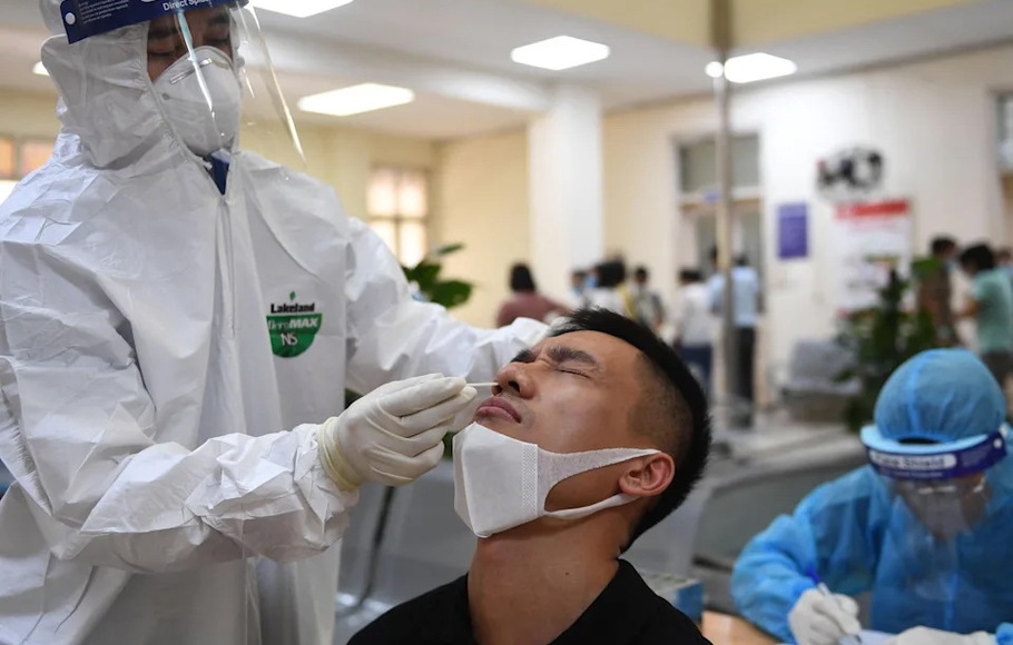 Petugas kesehatan melakukan tes Covid-19 pada seorang pria di Pusat Pengendalian dan Pencegahan Penyakit Hanoi pada 22 Mei 2021.