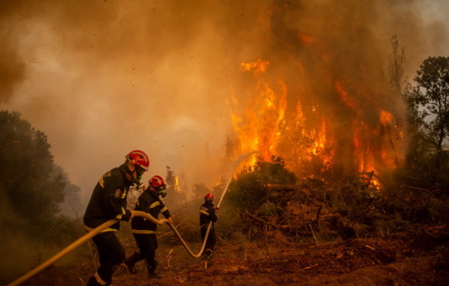Petugas pemadam kebakaran Serbia menggunakan selang air untuk memadamkan kobaran api kebakaran hutan di desa Glatsona di pulau Evia (Euboea), Yunani pada Senin 9 Agustus 2021. 