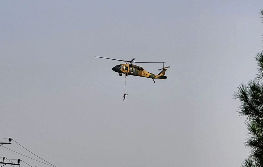 Helikopter Black Hawk dengan seorang pejuang Taliban bergelantungan. 
