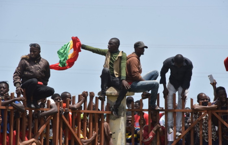 Seorang pria mengibarkan bendera nasional Guinea saat menyambut Pasukan Khusus Guinea yang tiba di Istana Rakyat di Conakry pada Senin 6 September 2021, menjelang pertemuan dengan para menteri mantan presiden Guinea, Alpha Conde. 