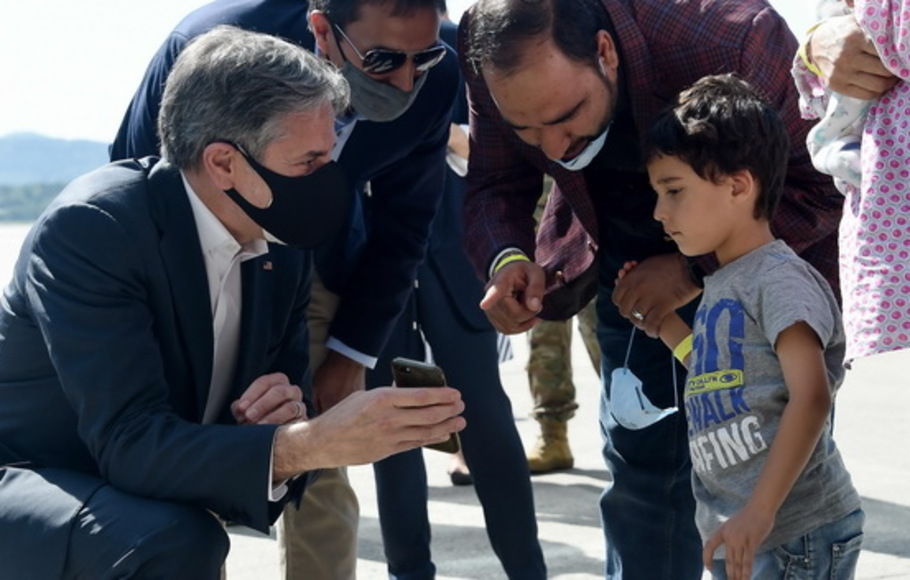 Menteri Luar Negeri AS Antony Blinken menunjukkan foto anak-anaknya di ponsel kepada seorang anak pengungsi Afghanistan di luar Hangar 5 untuk operasi evakuasi di Pangkalan Udara Ramstein, Jerman pada Rabu 8 September 2021. 