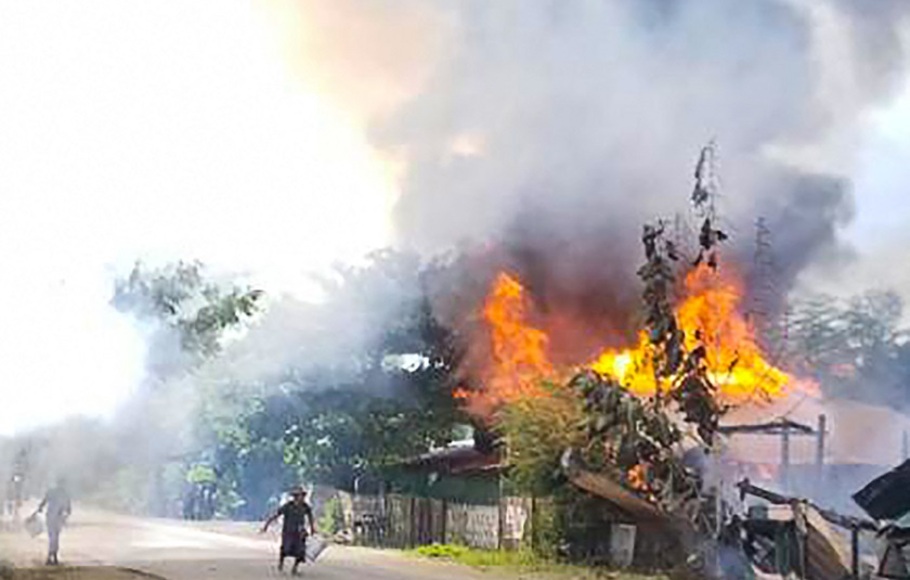 Gambar yang diambil pada 10 September 2021 menunjukkan warga yang berusaha memadamkan api ketika rumah-rumah terbakar di desa Namg Kar di kotapraja Gangaw wilayah Magwe, Myanmar, ketika pertempuran antara militer Myanmar dan milisi terjadi. 
