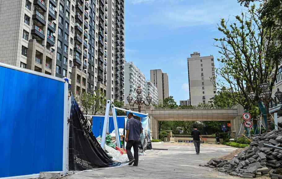 Seorang pria berjalan melintasi proyek apartemen Evergrande di Shanghai, 24 September 2021. 