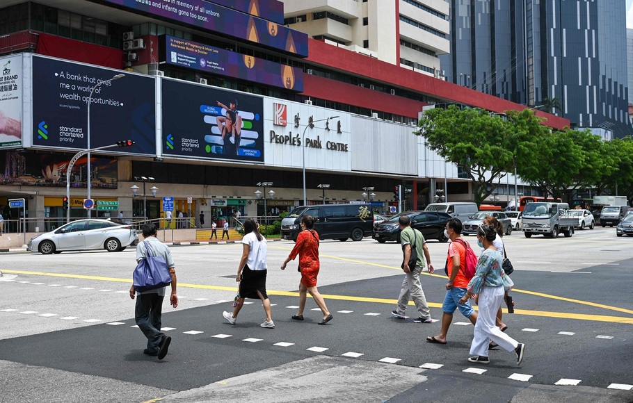 Orang-orang berjalan melintasi penyeberangan di distrik Chinatown di Singapura pada 4 Oktober 2021.
