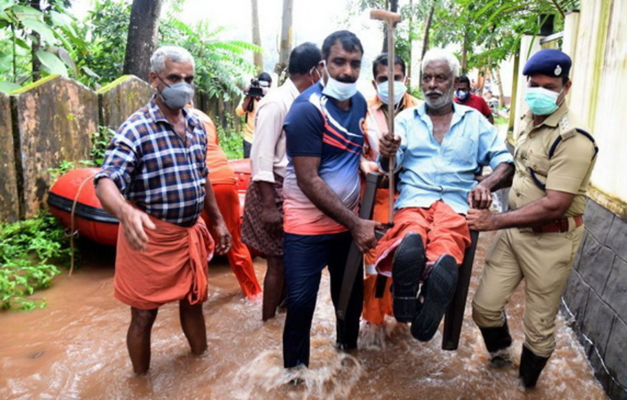 Tim penyelamat memindahkan seorang lelaki tua di distrik Alappuzha di negara bagian Kerala, India, Minggu 17 Oktober 2021. Hujan lebat melanda negara bagian itu pada Sabtu, memicu tanah longsor dan banjir. 
