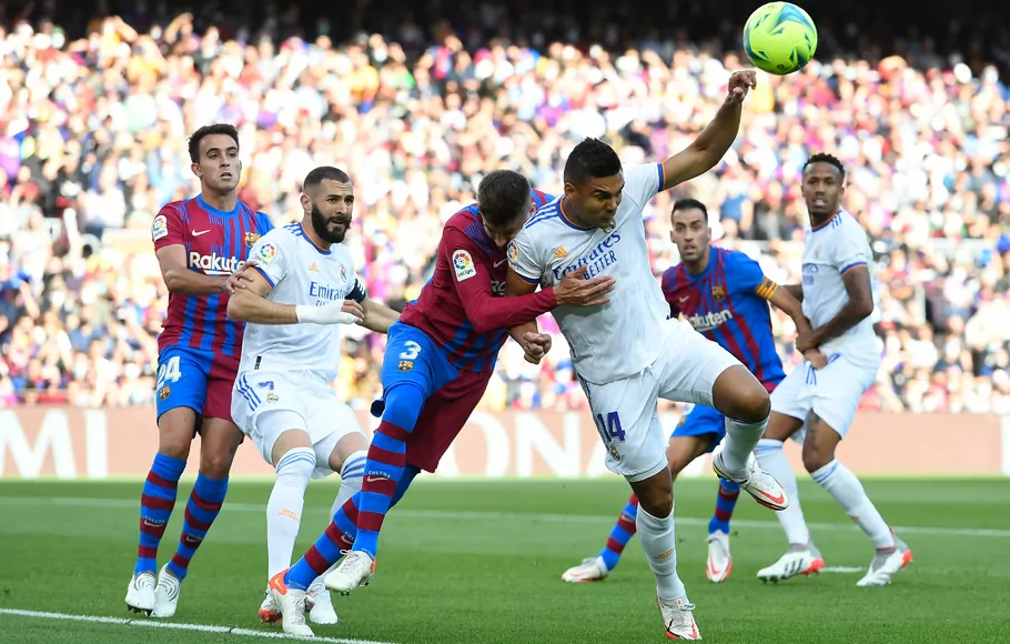 Bek Barcelona Gerard Pique berduel dengan gelandang Real Madrid Casemiro dalam pertandingan Liga Spanyol antara FC Barcelona dan Real Madrid di stadion Camp Nou, Barcelona, Minggu, 24 Oktober 2021.