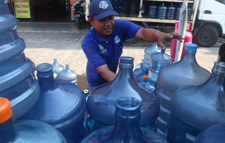 Pekerja agen air mineral menyusun galon air mineral, Jakarta, Selasa 26 Oktober 2021.