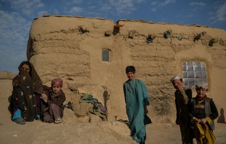 Satu keluarga Afghanistan berdiri di dekat rumah bata lumpur mereka di desa Haji Rashid Khan di distrik Bala Murghab. Gaya hidup Afghanistan menghasilkan 0,2 ton emisi CO2 per tahun, dibandingkan dengan 15 dari rata-rata orang Amerika, menurut data Bank Dunia. 
