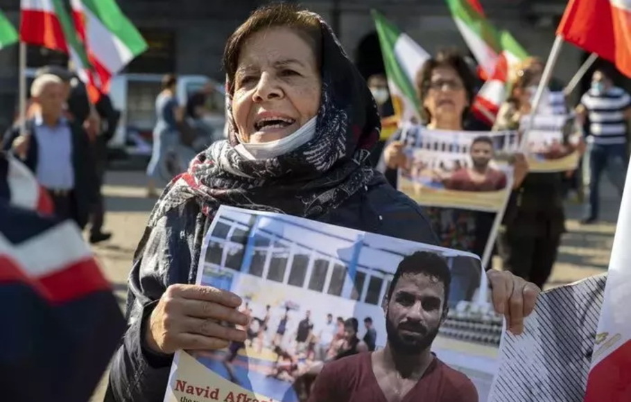 Seorang wanita memegang potret pegulat Iran Navid Afkari, saat demonstrasi pada 13 September 2020 di Amsterdam menentang eksekusi hukuman matinya di kota Shiraz di Iran selatan dan melawan pemerintah Iran. 
