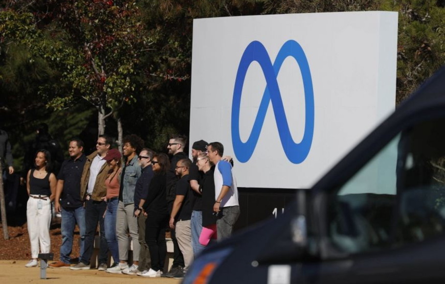 Karyawan Facebook berkumpul di depan tanda yang menampilkan logo baru dan nama 'Meta' di depan kantor pusat Facebook di Menlo Park, California, AS, pada Kamis 28 Oktober 2021.