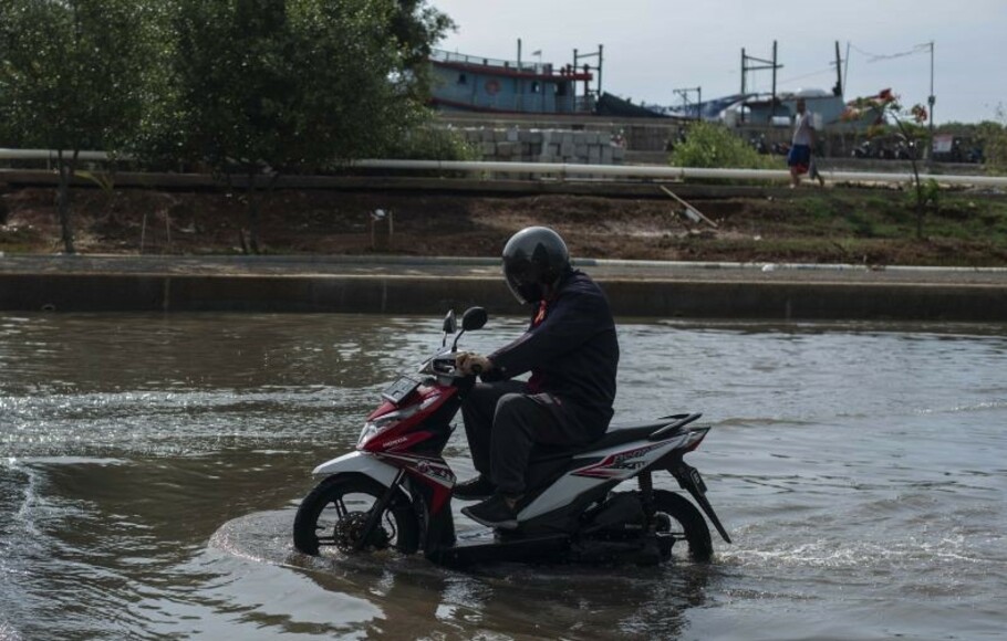 Sepeda motor melintasi banjir rob di kawasan Pelabuhan Perikanan Samudera Nizam Zachman, Muara Baru, Jakarta, Sabtu 6 November 2021. 