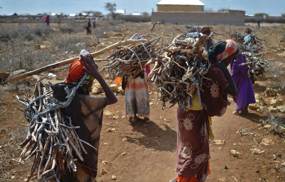 Para wanita membawa kayu bakar pada 15 Maret 2017 saat mereka berjalan kembali ke kamp darurat di pinggiran Baidoa, di wilayah Teluk barat daya Somalia, tempat ribuan pengungsi internal tiba setiap hari.