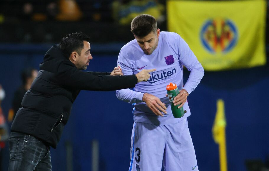 Pelatih Barcelona, Xavi Hernandez (kiri), memberi instruksi kepada bek Gerard Pique saat melawan Villarreal, dalam partai Liga Spanyol, Sabtu, 27 November 2021.